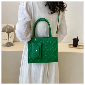 Detail of green leather handbag with clover embossing and detachable mini pouch accessory