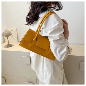 Chic yellow leather underarm bag shown on model with minimalist modern shoulder strap