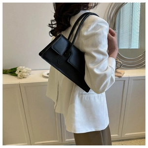 Detail of elegant black glossy leather underarm bag with flap and decorative strap