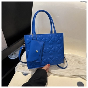 Detail of blue square handbag with clover embossing and detachable mini envelope pouch