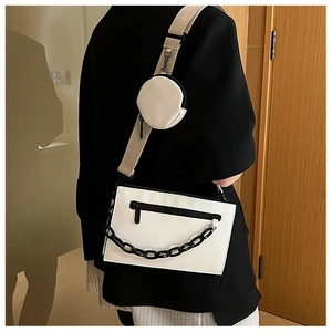 Detail of white rectangle crossbody bag with black chain and round coin purse on the strap