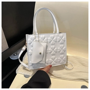 Detail of white rectangular handbag with clover relief, top handle and mini coin purse