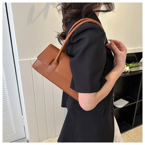 Caramel leather baguette bag shown from the back on a model wearing a black blazer