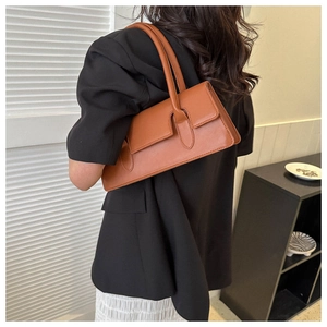 Detailed shoulder view of a caramel underarm baguette bag with slim leather straps