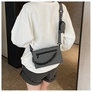 Detailed view of grey crossbody bag with chunky black chain and mini round coin pouch