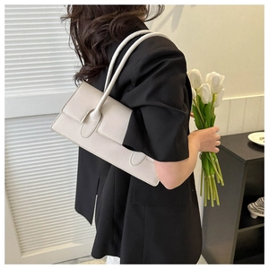 Chic cream white underarm bag shown on shoulder in a minimalist interior setting