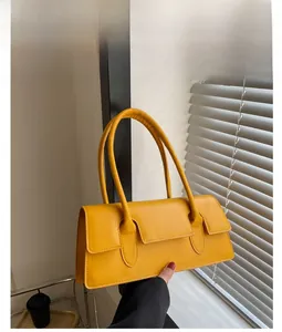Detail of yellow rectangular handbag with magnetic flap closure and long shoulder strap