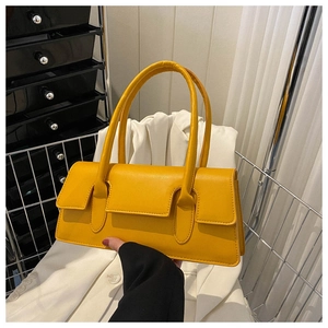 Macro shot of bright yellow baguette bag showing the sleek leather texture and handle detail