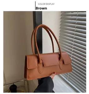 Detailed close-up of a brown synthetic leather underarm bag with slim shoulder straps