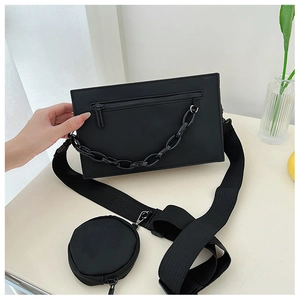 Détail du sac bandoulière en nylon noir avec chaîne mate et petite pochette ronde