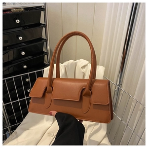 Detailed side view of a brown faux leather underarm bag with unique curved flap and slim handles