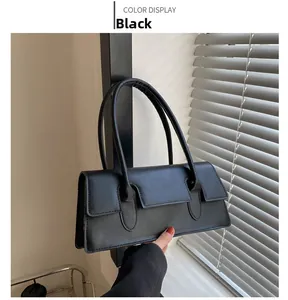 Detail of minimalist black rectangle handbag with sleek flap and long straps in natural light