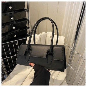 Detailed close-up of a structured black matte leather handbag with long flap and top handles