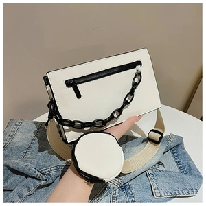 Détail du sac bandoulière blanc avec chaîne noire et mini pochette ronde assortie