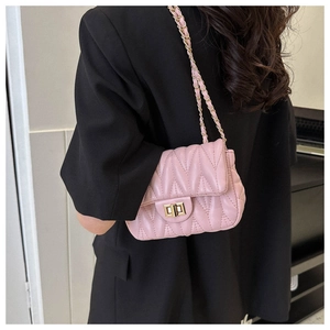 Detail of pink quilted shoulder bag with golden chain strap and V-pattern stitching