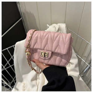 Close-up of pink quilted crossbody bag with gold chain and metal ball decoration