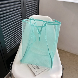 Bolso tote grande de malla verde menta con asas resistentes en silla minimalista