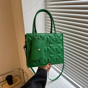 Green vintage handbag with embossed clover patterns and a small matching envelope pouch