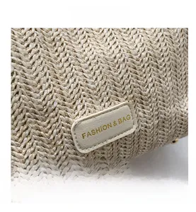 Vue macro de la paille tressée beige avec un patch en cuir doré marqué FASHION & BAG