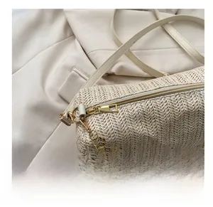 Détail du sac baguette tissé beige avec fermeture éclair dorée et bandoulière fleurie