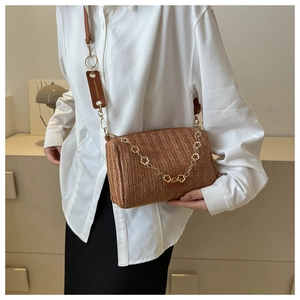 Détail du sac bandoulière tissé marron avec chaîne dorée à fleurs et lanière en cuir