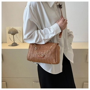 Détail du sac tissé avec chaîne à fleurs dorées et bandoulière en cuir