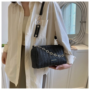 Détail du sac baril noir tissé avec chaîne dorée florale et bandoulière de marque