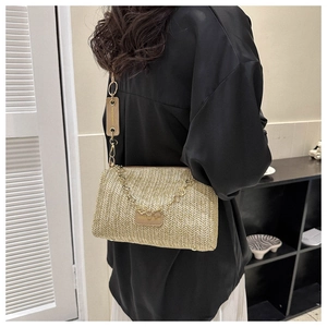 Détail de la texture en paille naturelle et chaîne dorée du sac à bandoulière