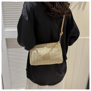 Détail d'un sac à bandoulière en paille beige avec chaîne et étiquette de mode
