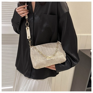 Détail d'un sac bandoulière en paille tressée avec chaîne dorée et lettrage de mode