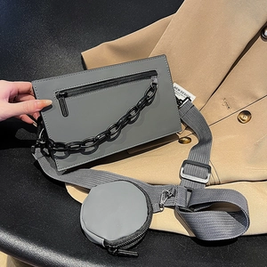 Sac bandoulière gris foncé avec chaîne en métal et petit porte-monnaie sur la sangle