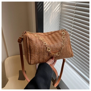 Détail du sac bandoulière tressé marron avec chaîne à fleurs dorées et bandoulière en cuir