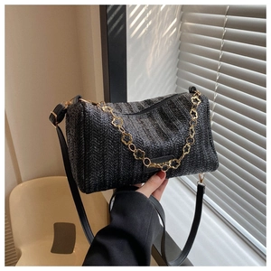 Vue détaillée du sac cylindrique tressé noir avec chaîne florale dorée et bandoulière cuir