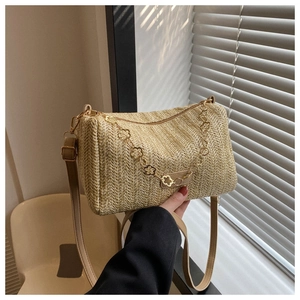 Détail du sac cylindrique en paille avec chaîne fleurie dorée et bandoulière