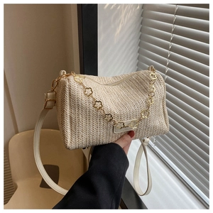 Vue détaillée du sac cylindrique tressé beige avec chaîne dorée à fleurs et bandoulière