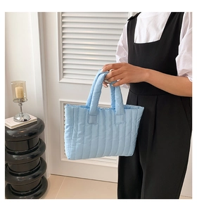 Detail view of light blue quilted puffer tote bag with vertical stitching and large capacity