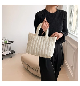 Close-up of cream quilted tote bag showing soft vertical padding and high-quality nylon texture