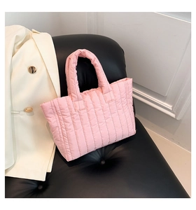 Pink quilted tote bag with soft padded handles shown on a black leather chair