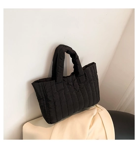 Detailed view of black quilted nylon tote bag with vertical padded stitching design
