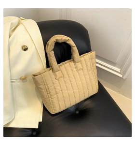 Detailed view of quilted puffer tote bag on leather chair with stylish blazer