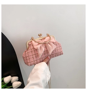 Détail d'un sac en tweed rose avec grand nœud en satin et poignée en métal doré sur fond blanc