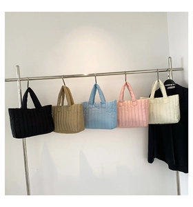 Vertical quilted tote bags displayed in black, khaki, blue, pink, and cream colors