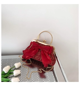 Détail d'un sac en tweed rouge avec nœud en soie et bandoulière chaîne dorée élégante