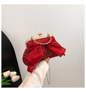 Gros plan d'une pochette en tweed rouge avec nœud en satin et poignée dorée