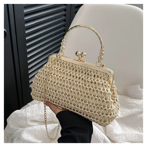 Dettaglio borsa in paglia intrecciata con manico in metallo dorato e decoro floreale
