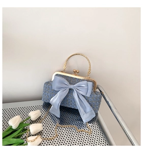 Détail du sac en tweed bleu avec noeud organza et chaîne dorée sur étagère métallique