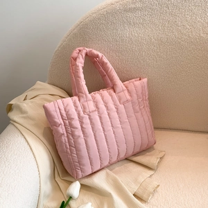 Pink quilted puffer tote bag on a plush white sofa with decorative white tulips