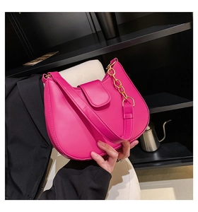 Détail du sac demi-lune rose vif avec fermeture à rabat et chaîne dorée chic