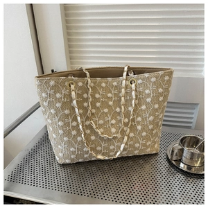 Dettaglio del ricamo floreale bianco su una borsa tote in paglia beige naturale