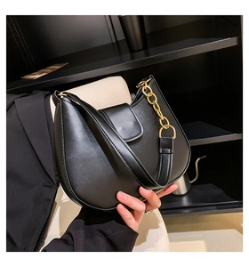 Détail du sac demi-lune noir en cuir mat avec une grosse bandoulière en chaîne dorée